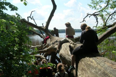 Fastenhof - Teilnehmer sitzen am See auf einem Baumstamm
